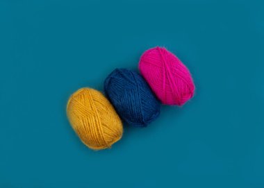 Mavi arka planda izole edilmiş çok renkli yün örme ipliği topları.