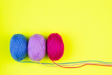 Sarı arka planda izole edilmiş çok renkli yün örme ipliği topları.