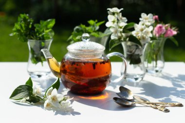 Gül, yasemin ve nane yaprakları Türk cam bardaklarında. Bitki çayı için malzemeler. Yaz güneşi ve gölge.
