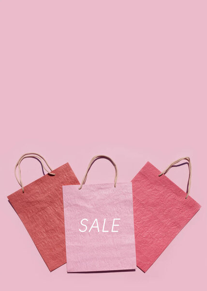 Colourful textured paper shopping bags on pink background. Minimal fashion shopping online concept. Copy space, top view, flat lay. Mock up.