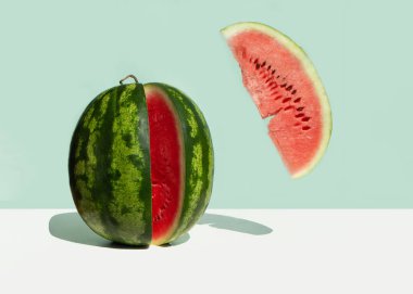 Büyük, taze bir karpuz ve naneli arkaplanda kırmızı bir karpuz dilimi. Yaz meyvelerinin yaratıcı minimum konsepti. Havalandırma yemeği.