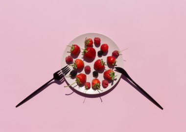 Taze böğürtlen, çilek, ahududu, pembe arka planda pembe seramik tabakta böğürtlen. Vejetaryen ya da meyve diyeti konsepti. Üst görünüm.