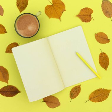 Sarı gölgeli sonbahar kompozisyonu. Düz not defteri, kahve ve sonbahar kuru yaprakları. Liste yapmak için Üst Görünümü Düzenle