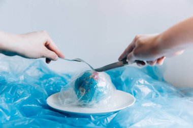 Seyyare yerküre plastik bir plaka üzerinde bir çatal ve bıçak bir insan tarafından yemiş kaplı. Plastik kirliliği ve atık kavramı. İnsan etkisi - çöp plastik. Küresel ısınma sorunu. 