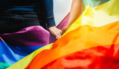 Yeşil bir çayırda elinde Gay Gökkuşağı Bayrağı tutan kadın. Aynı cinsiyet çiftleri için mutluluk, özgürlük ve aşk kavramı. 