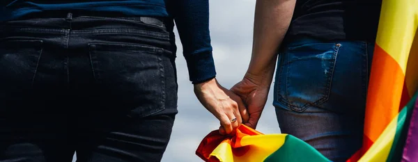 Yeşil bir çayırda elinde Gay Gökkuşağı Bayrağı tutan kadın. Aynı cinsiyet çiftleri için mutluluk, özgürlük ve aşk kavramı. 