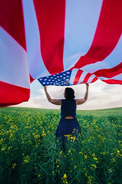 一个女人在外面的草地上举着美国国旗7月4日至独立日 — 图库照片