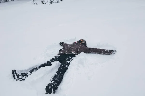 Woman doing a snow angel in heavy snow. Winter time.