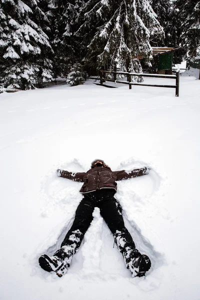 Woman doing a snow angel in heavy snow. Winter time.