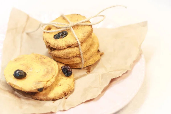 Cookies with raisins on a pink plate. Packing cookies in Kraft paper. Open space for recipes