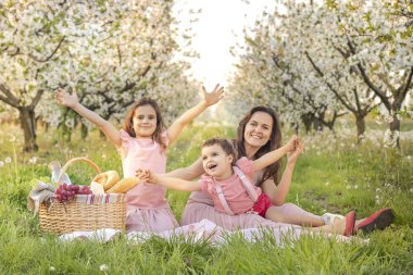 Mutlu bir aile! Çiçekli bahçelerde doğada piknik. Anneler günün kutlu olsun! Doğum günün kutlu olsun! insanlar, tatiller ve aile kavramı - mutlu anne ve çocuklar