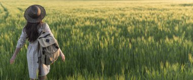 Özgürlük. Buğday tarlasında sırt çantası olan gezgin. Mutlu kadın elleri açık açık havada