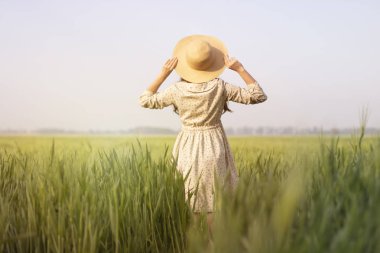 hasır şapkalı buğday tarlasında güzel, mutlu bir kadın. Çiğ buğdaylı çiftçi. Güzellik ve bakım kavramı. Yaşam tarzı. Organik tarım. Doğada yaşam, yeni hayat, taze buğday hasadı