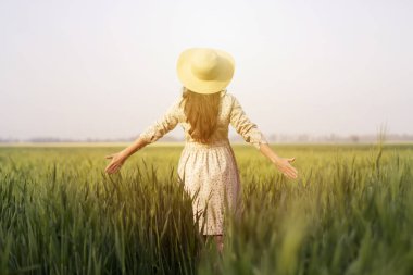 hasır şapkalı buğday tarlasında güzel, mutlu bir kadın. Çiğ buğdaylı çiftçi. Güzellik ve bakım kavramı. Yaşam tarzı. Organik tarım. Doğada yaşam, yeni hayat, taze buğday hasadı