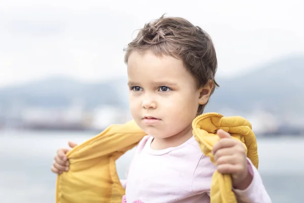 Happy child, boy in yellow vest on blue background. The concept  look into the future, to open the soul