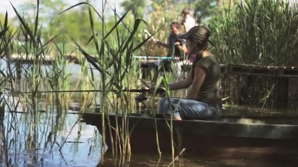 Fiatal nő halász a halászat az erdei tó, kezében a horgászbot csavarják a tekercs. — Stock videók