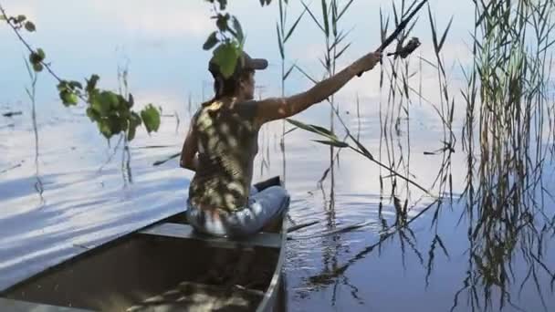 Νέα γυναίκα ψαράς ψαρεύει στη λίμνη του δάσους, κρατώντας το καλάμι ψαρέματος αναστρέφει το πηνίο. — Αρχείο Βίντεο