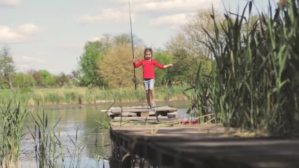 Child fishing girl on the lake at the pier. — Stock Video