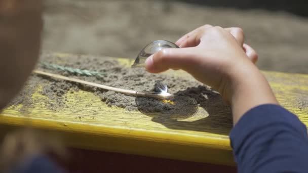 Děti, které spalují dřevěné sklo pomocí lupy na slunci, paprscích nebo slunci — Stock video