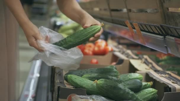Молодая мама покупает огурцы в супермаркете — стоковое видео