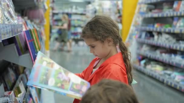 Małe dziewczynki kupują książki w supermarkecie — Wideo stockowe
