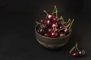 Siyah arka plan üzerinde taze tatlı kiraz kase. Sağlıklı gıda konsepti, bitki arka planı, doğal eko-ürünler, organik gıda, vejetaryen, çiğ, festival gıda, sanat