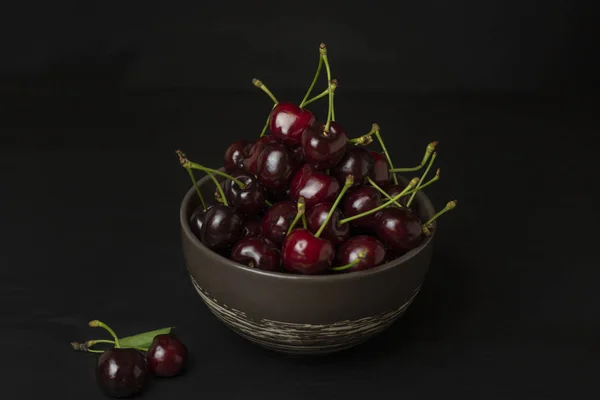 Fresh sweet cherries bowl on black background. Healthy food concept, plant background, natural eco-products, organic food, vegetarian, raw, festival food, art