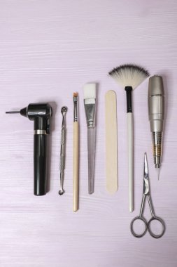 Kozmetoloji araçları: estetik, kaş dövme fırçası, makas, krem tüp, hafif bir arka plan üzerinde kavanoz