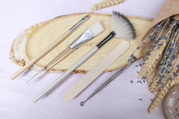 Cosmetology tools: aesthetics, eyebrow tattoo brush, scissors, cream tube, jar on a light background