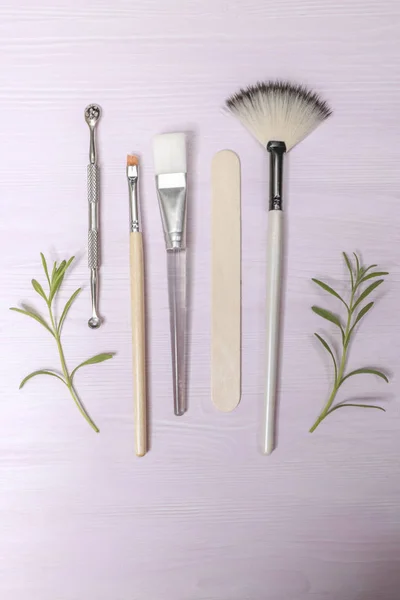 Cosmetology tools: aesthetics, eyebrow tattoo brush, scissors, cream tube, jar on a light background