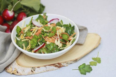 Yeşillik ve turp, havuç ve ıspanak yaprakları ile taze sebze salatası. Rustik tarzda ahşap bir stand üzerinde, masada hizmet veren güzel salata. sağlıklı gıda, organik gıda, vejetaryen bir kez