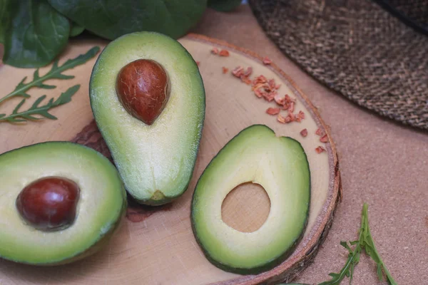 Avocado on a wooden Board with the spinach leaves. Fresh avocado sliced on vintage wooden background closeup. Ripe green avocado fruit on a wooden Board. Healthy food concept, organic food, vegetarian