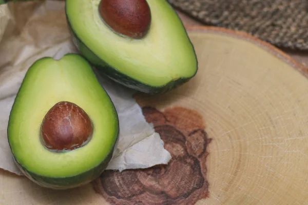 Avocado on a wooden Board with the spinach leaves. Fresh avocado sliced on vintage wooden background closeup. Ripe green avocado fruit on a wooden Board. Healthy food concept, organic food, vegetarian