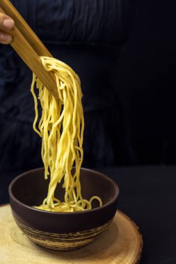 Eller siyah bir arka plan üzerinde makarna tabağına uygulanır. Sağlıklı gıda konsepti, bitki arka planı, doğal eko-ürünler, organik gıda, vejetaryen, sebze, çiğ, gıda sanatı