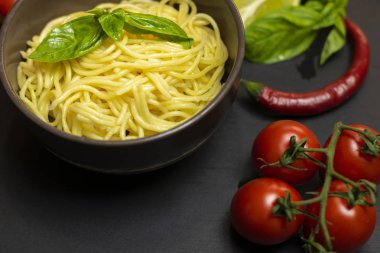 İtalyan gıda maddeleri: makarna, zeytin, domates salçası, domates, kireç, zeytinyağı, siyah bir arka plan üzerinde Fesleğen. Sağlıklı gıda konsepti, bitki arka planı, doğal eko-ürünler, organik gıda, vejetaryen