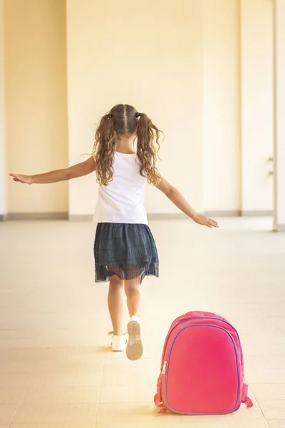 first day of school. Girl schoolgirl goes to first grade. Girl playing, running after school