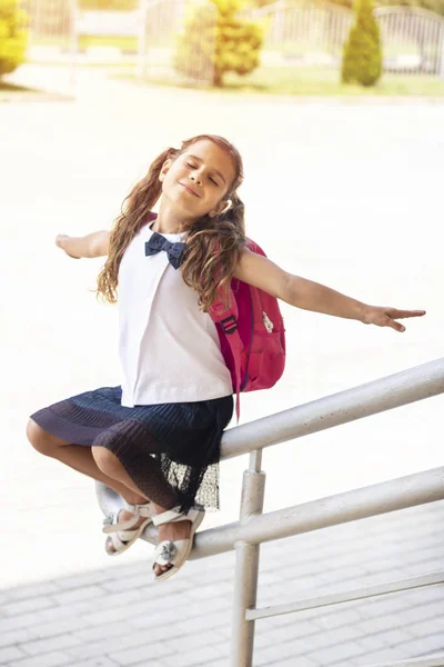 first day of school. Girl schoolgirl goes to first grade. Girl sitting near the school and waiting for a lesson