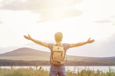 Gün batımı ve dağlara karşı mesafe bakarak bir sırt çantası ile Adam turist