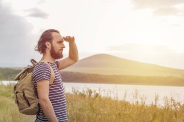 Gün batımı ve dağlara karşı mesafe bakarak bir sırt çantası ile Adam turist