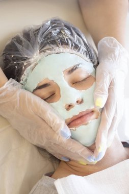 Doktor güzellik uzmanı genç ve güzel bir kadına yüz maskesi taktı. Kozmetoloji cilt bakımı, güzellik