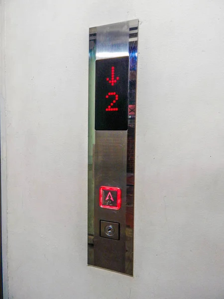 Elevator controls in the wall with a red button on and the number two in the display