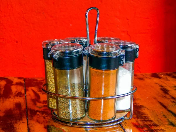 Spice rack over a table with orange wall in the backgroundbg