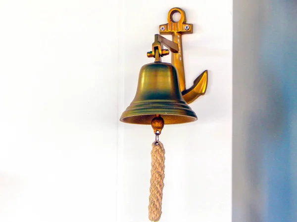 Metal bell with rope on white wall