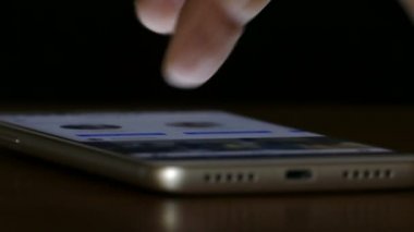 Karanlıkta dokunmatik ekranda akıllı telefon arayan bir adamın eli.