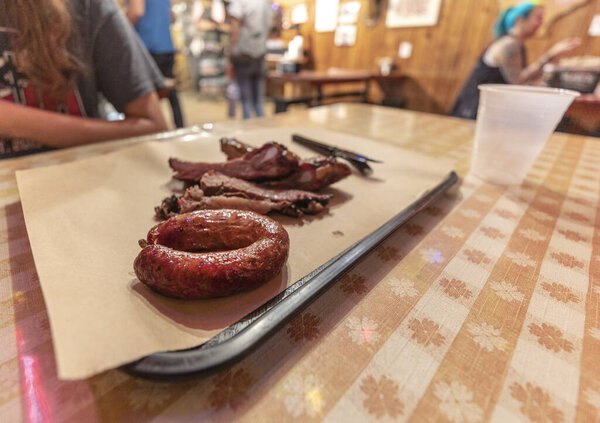 Lockhart, Texas, USA - March 15, 2025: Smoked beef brisket and sausage served on butcher paper with knife at Black's Barbecue restaurant table in Lockhart, Texas