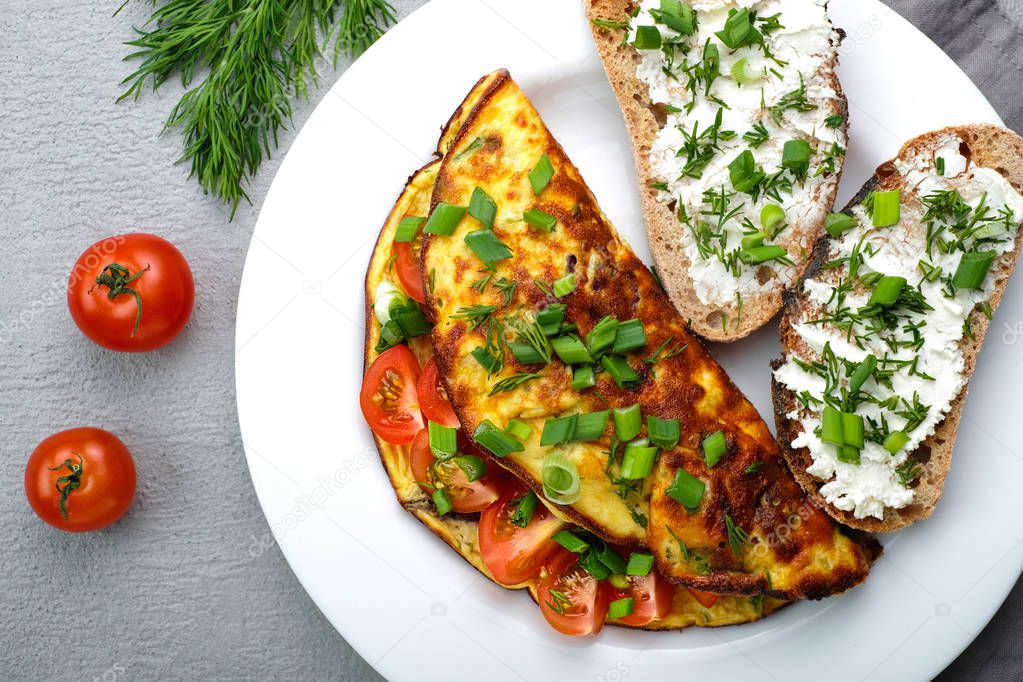 Omelette with cherry tomatoes, toasts with cream cheese and greenery