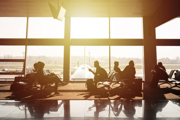 Внутри терминала аэропорта. Пассажиры ждут вылета. Большое окно и arplane на заднем плане
.