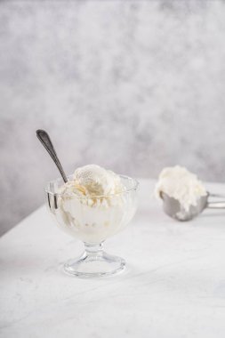 Cam bir kasede vanilyalı dondurma. Arka planda dondurma kepçe.