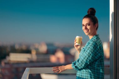 Pijamalı bir kadın Balkonda kahve içiyor