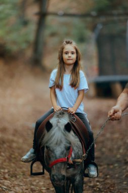 Bir eğitmen tarafından tutulan Sevimli Midilliye Binen Küçük Kız